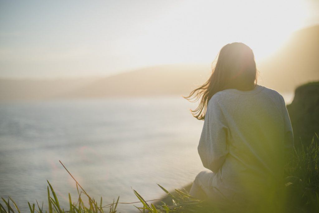 woman looking out into the ocean as stress management and relaxation