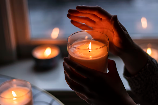 A hand held over a lit candle, honoring a lost loved one in grief therapy.