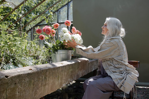 An older woman tending flowers, honoring her losses through grief therapy.