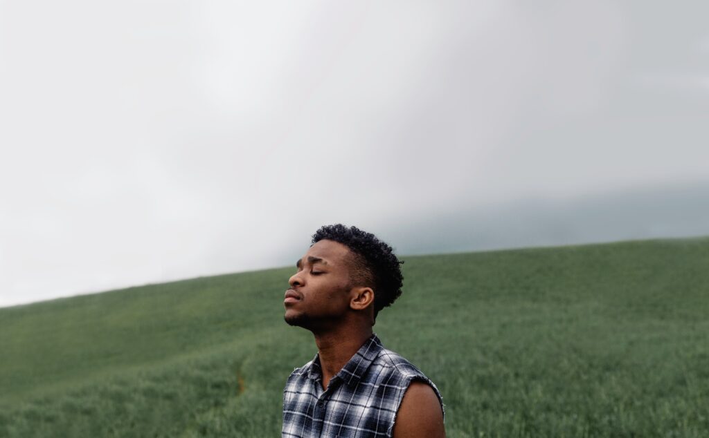 LGBTQIA person standing in a field, considering seeking holistic therapy