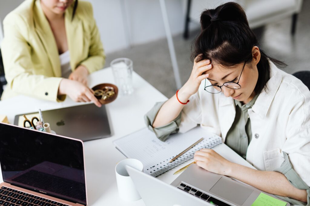 woman with her head in her hand stressed at her work desk