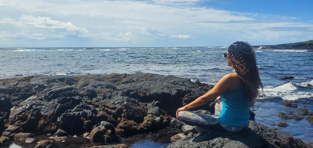 a woman on a New Jersey beach in a yoga pose working towards holistic healing