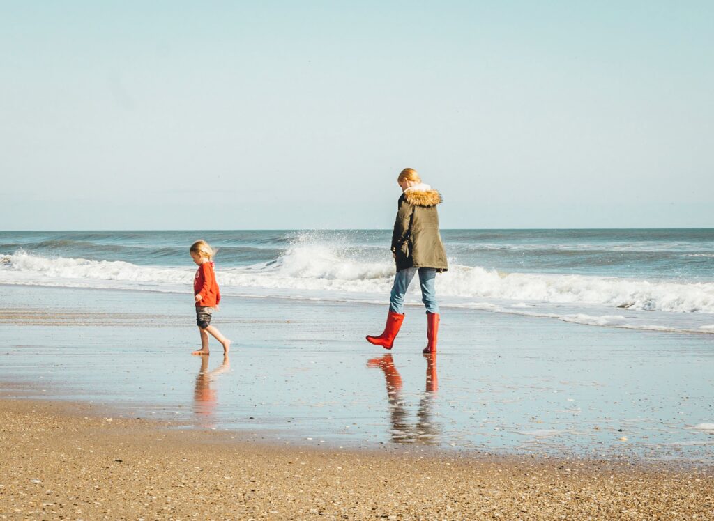 a woman and child walk on the beach, representing inner child healing