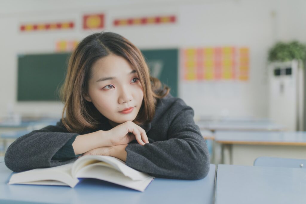 a teen sits at her desk with a book thinking about navigating the new school year