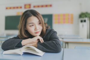 a teen sits at her desk with a book thinking about navigating the new school year