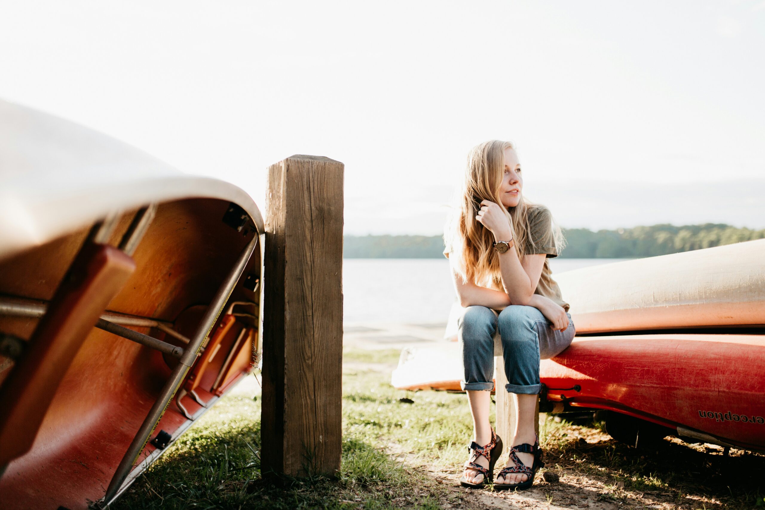 woman sitting on a beach with kayaks deep in thought about healing trauma