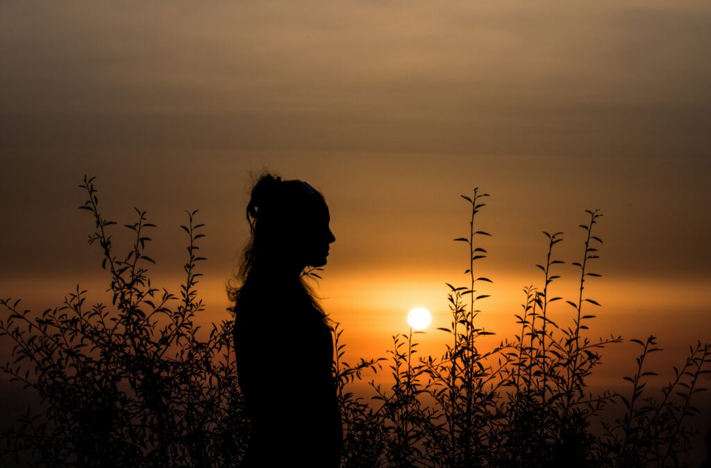 woman's silhouette against a sunset sky as she considers complex trauma and healing
