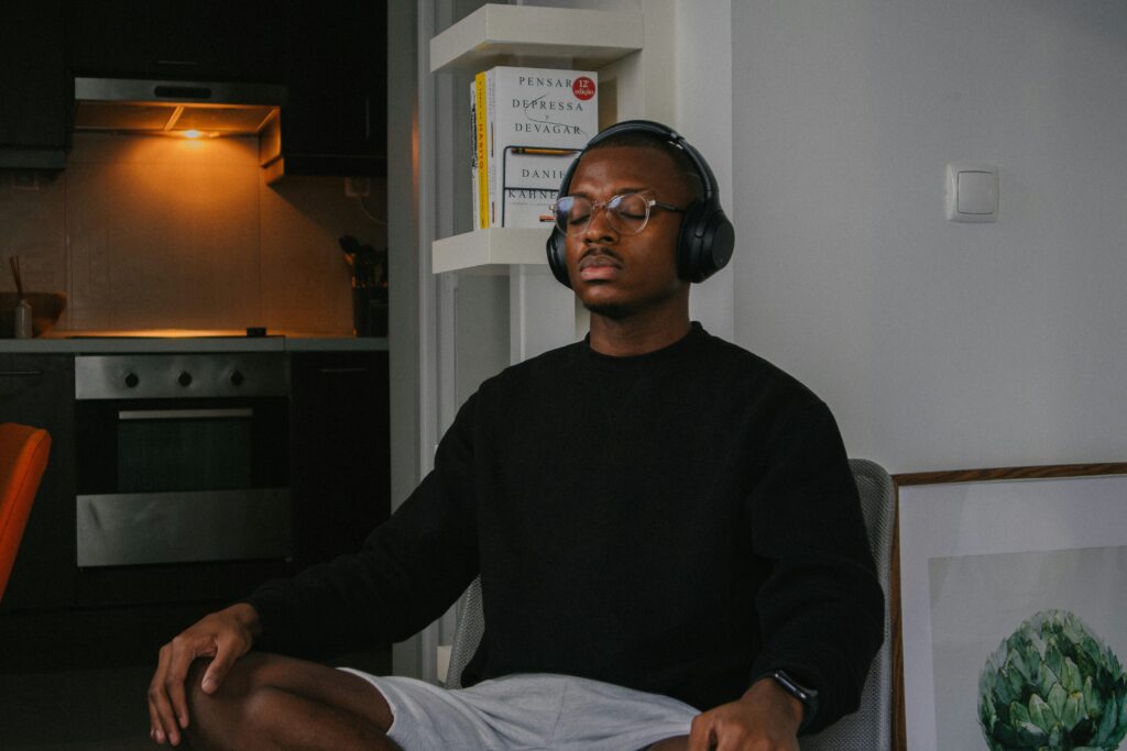 black man meditating in a dimly lit room wearing headphones