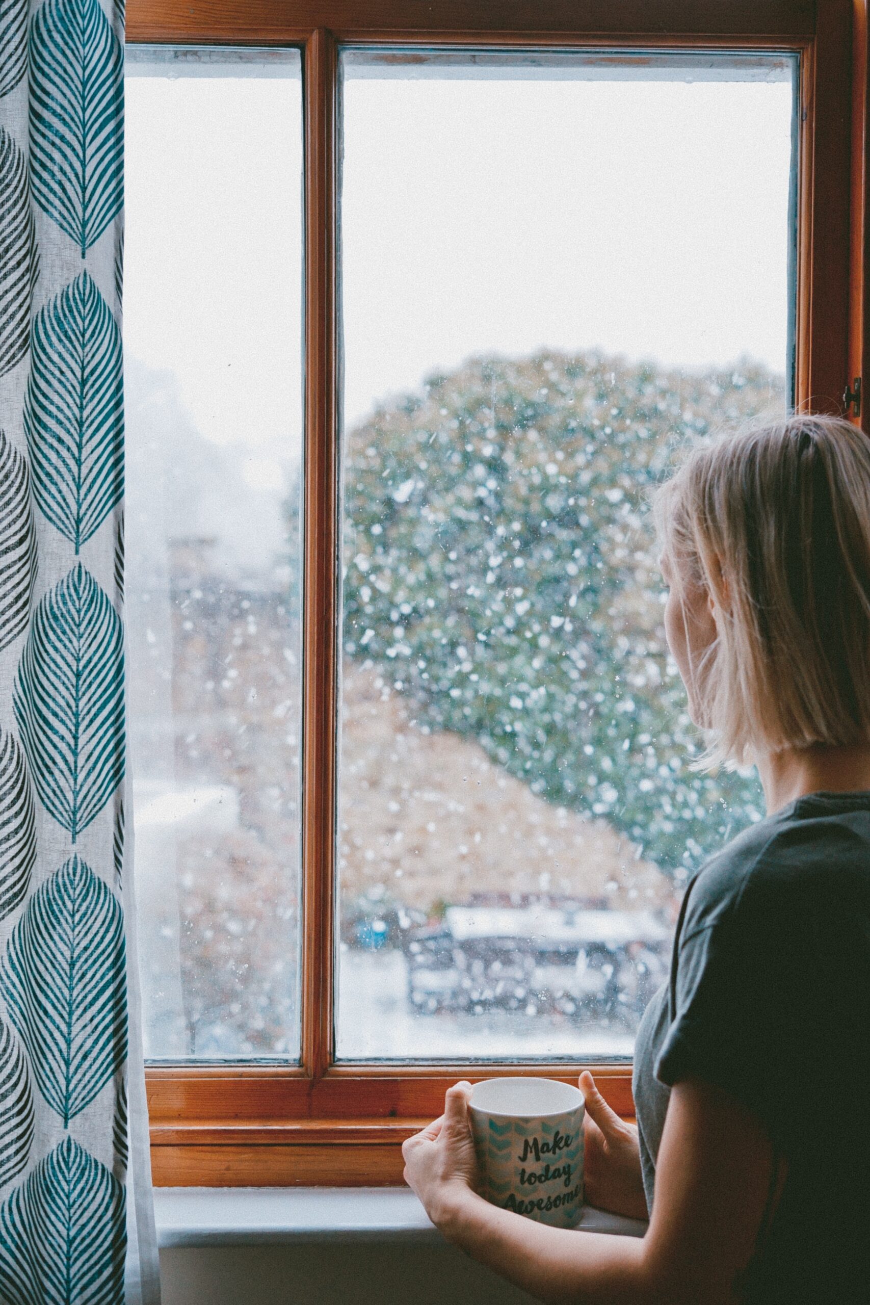 woman with ginger tea looking out the window