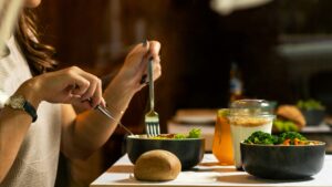 Two hands cutting into healthy, whole foods on a table. The food is not ultra-processed, because the eater has learned from Awakened Path in New Jersey that the impacts of ultra-processed foods are serious.