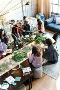 A group of people using greenery to make art. They are laughing and having fun, enjoying their connection and using art and community to build their motivation in their lives, because of the teachings of therapists at Awakened Path Counseling in New Jersey.