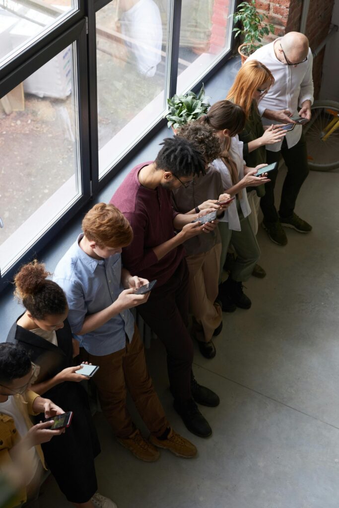 A group of people all suffering from constant busyness on their phones. They would benefit from the advice of holistic therapists at Awakened Path in New Jersey.