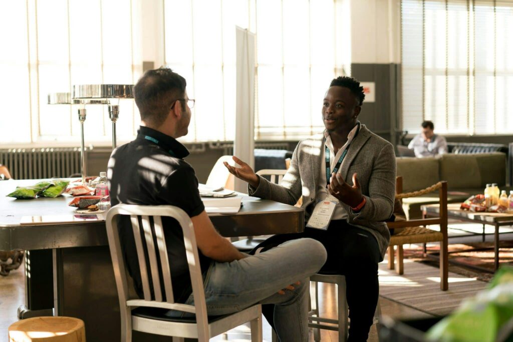 Two men are sitting and expressing their emotions in a healthy way while talking with each other in New Jersey. They've learned from their therapists at Awakened Path about healthy ways to access and express their emotions.