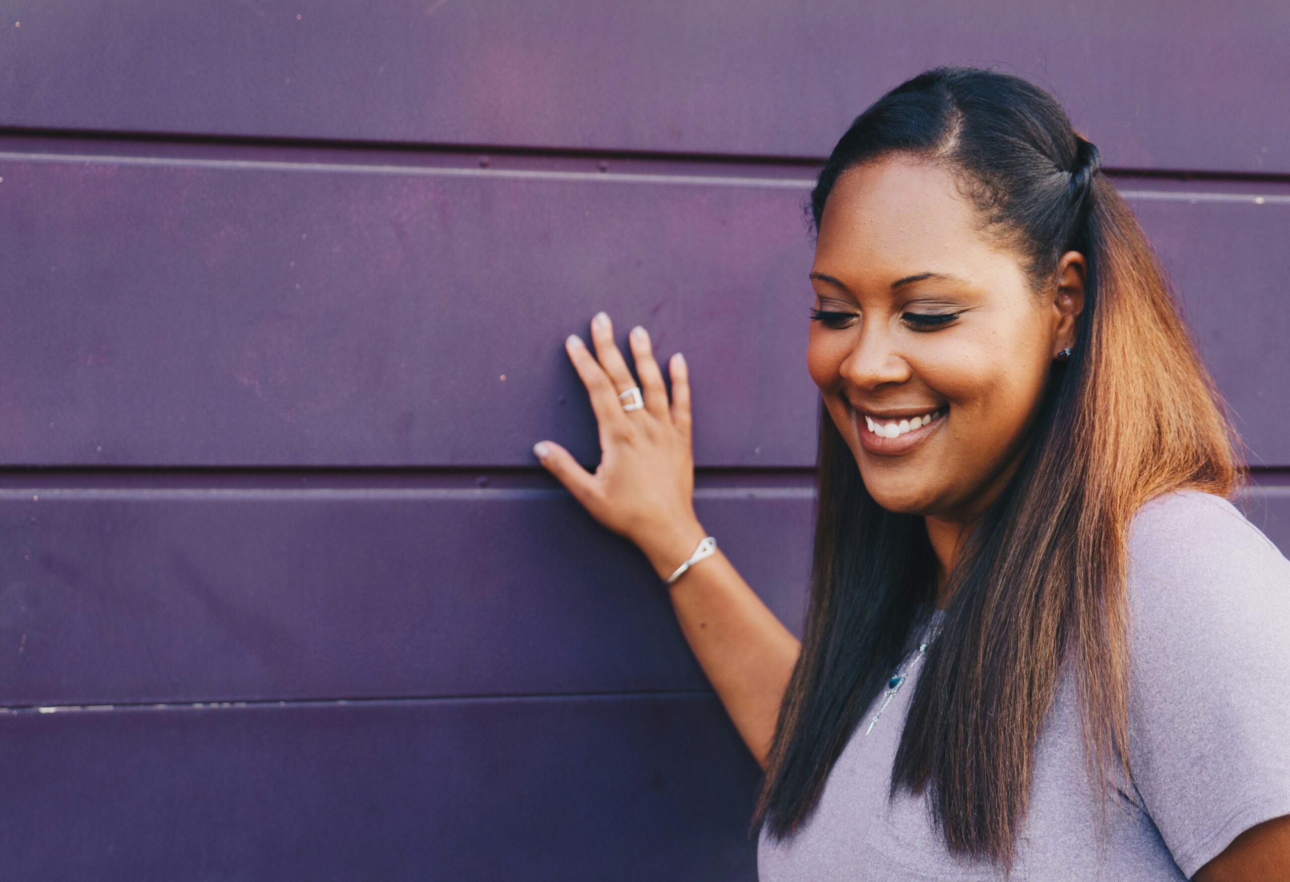 woman laughs against purple wall after setting boundaries