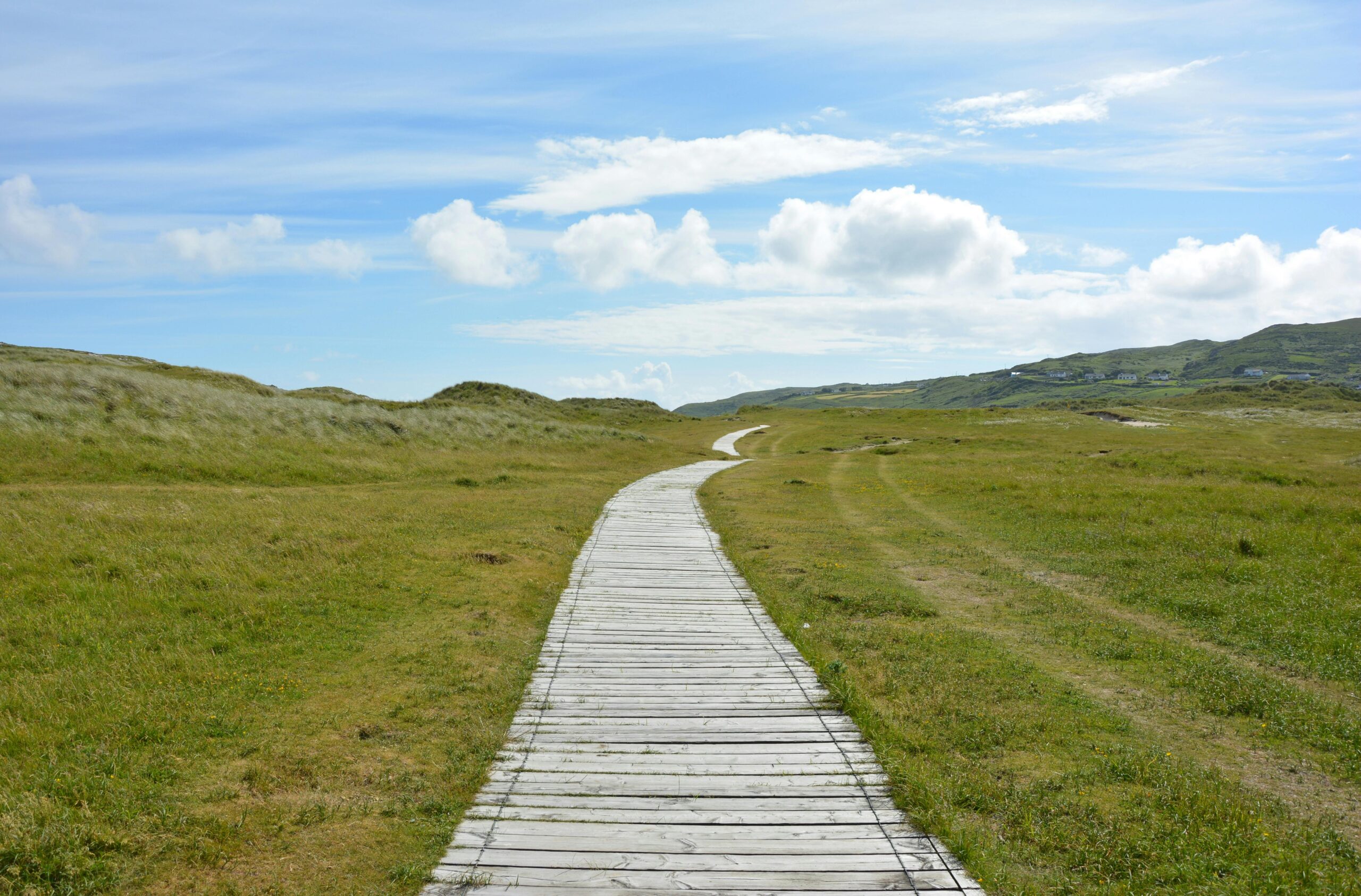 path along grass with blue sky ahead representing grass is greener syndrome