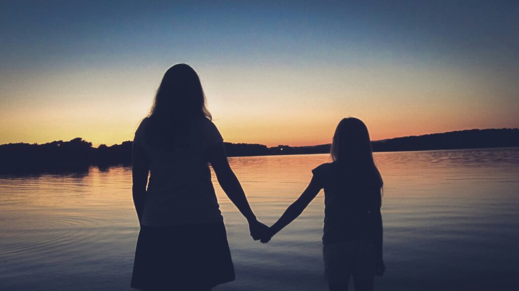an adult and child silhouette holding hands representing inner child healing