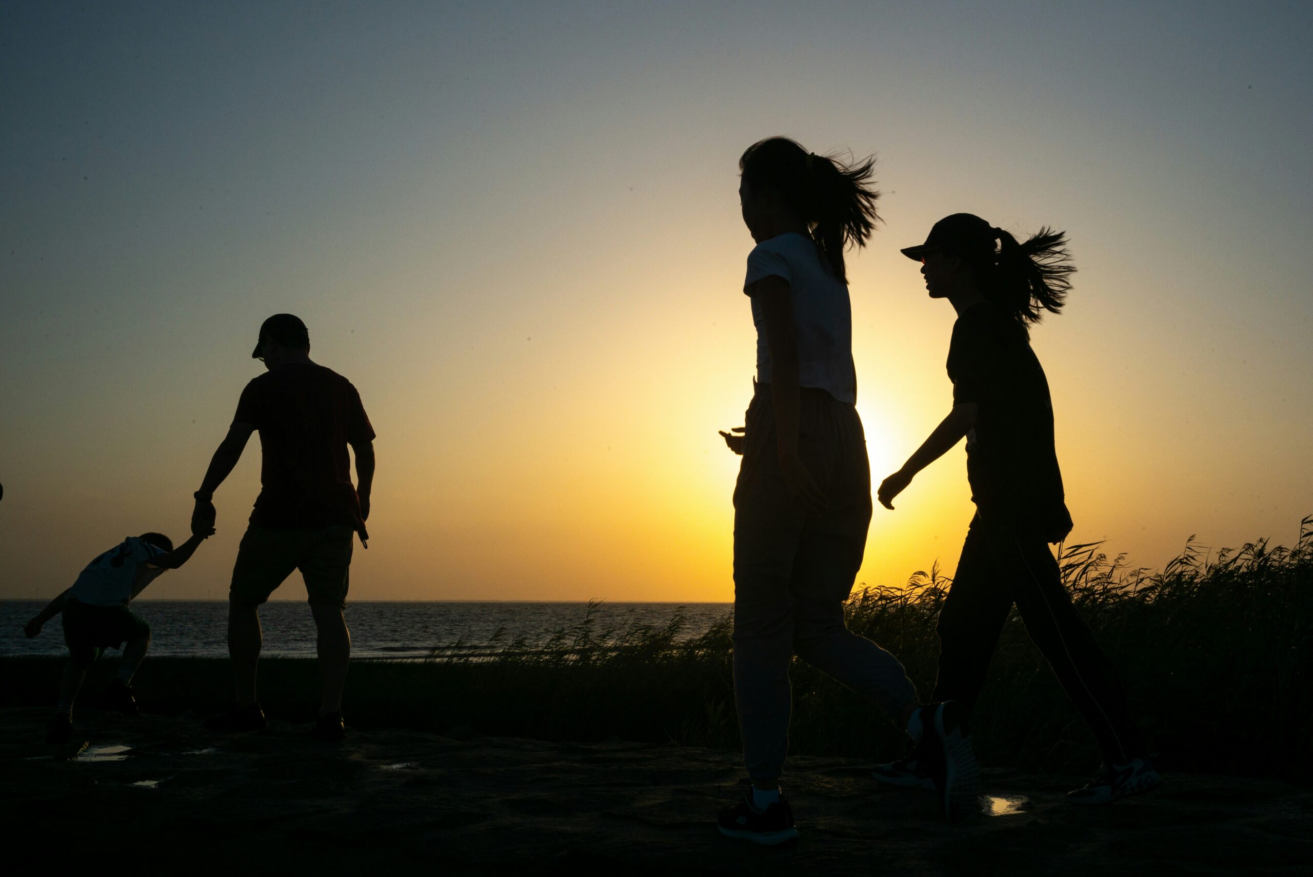 family silhouette in front of a beach sunset family having fun after overcoming teen screen addiction