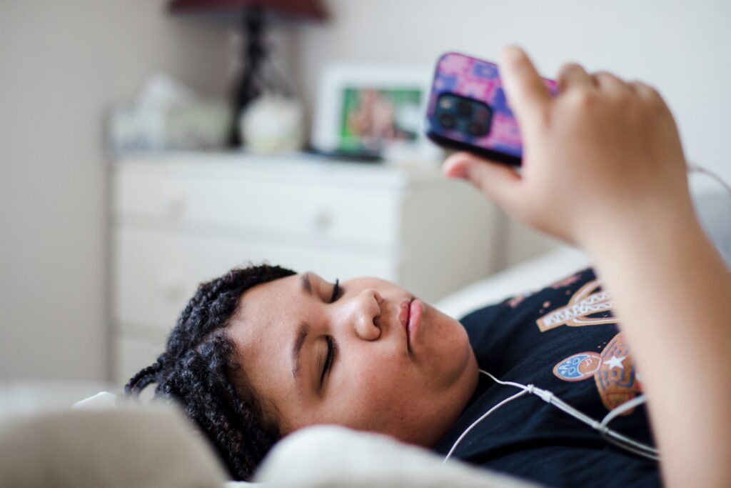 teen in bed addicted to her phone scrolling