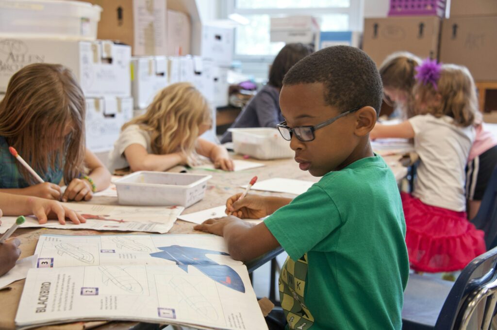 Child focused on completing schoolwork at a desk in a classroom, practicing concentration and confidence for the new school year.