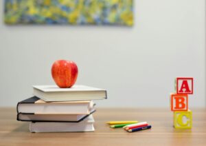 Stack of colorful books and learning blocks on a classroom desk, symbolizing preparation, engagement, and holistic support for children returning to school.