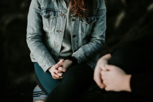 A person in a denim jacket sitting with a therapist during a counseling session, illustrating the human connection and empathy that make real therapy effective compared to AI chatbots.