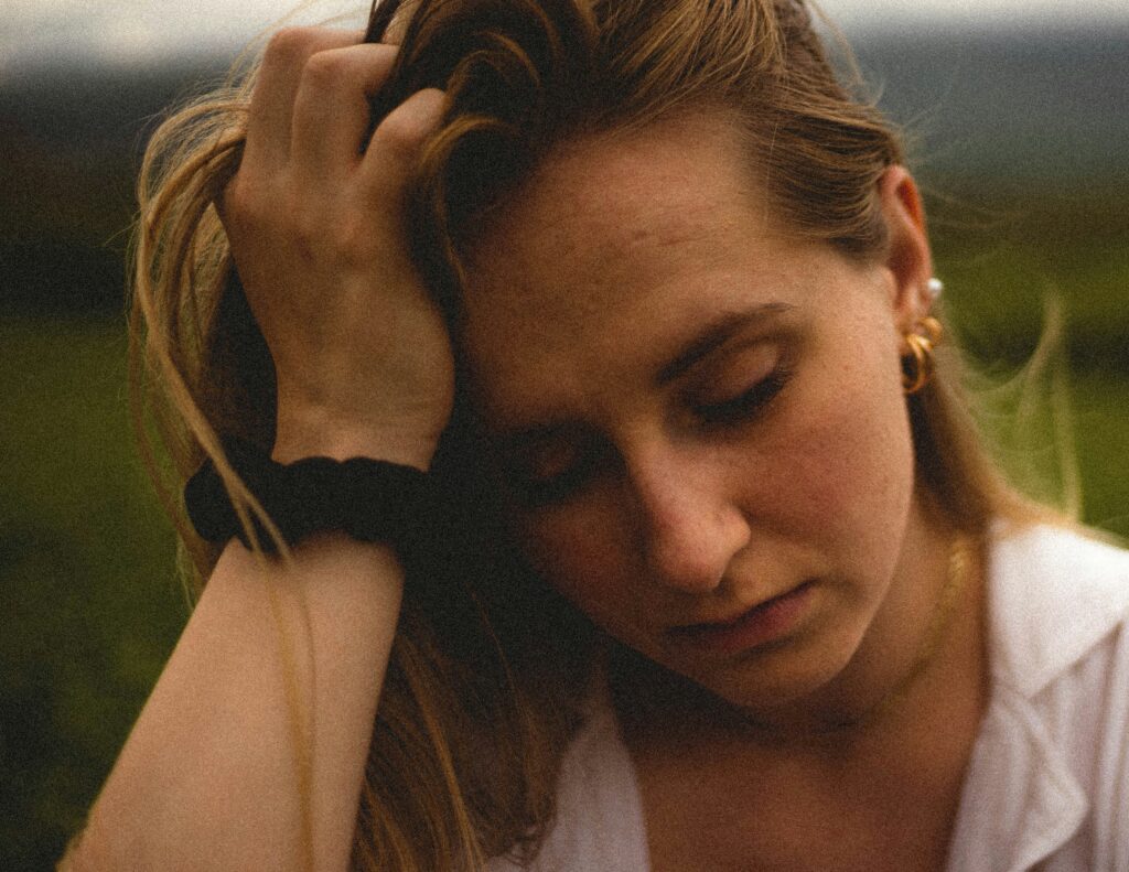 Close-up of a woman with her head resting on her hand, capturing the emotional weight of betrayal trauma, ambiguous loss, and grief without closure