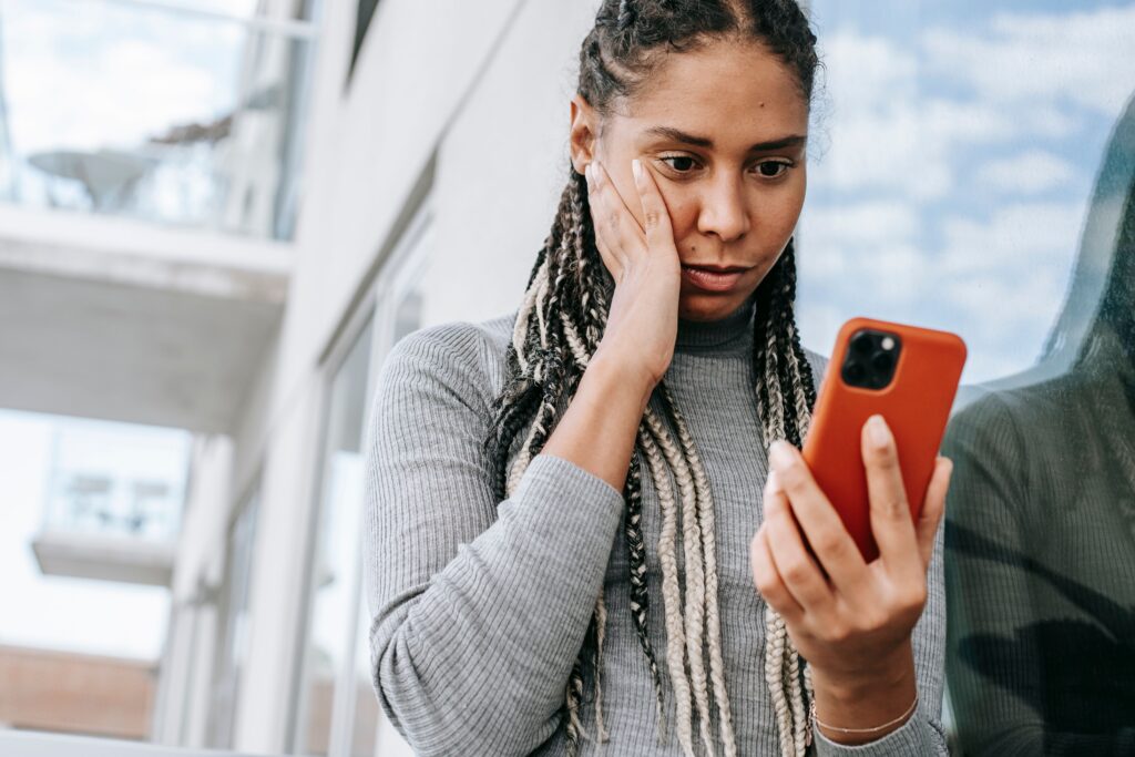 Woman looking anxiously at her phone, illustrating doomscrolling, social media stress, and the mental health impact of constant online information