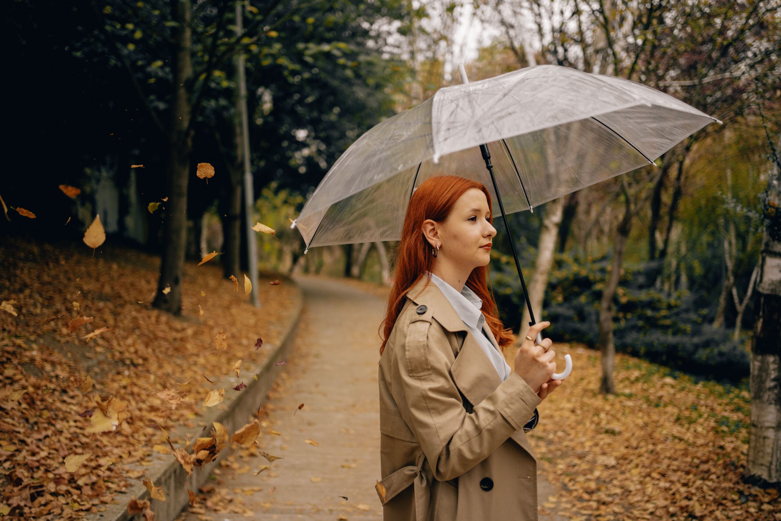 Woman walking through an autumn park with an umbrella, representing overcoming fear, building confidence, and personal growth outside your comfort zone.